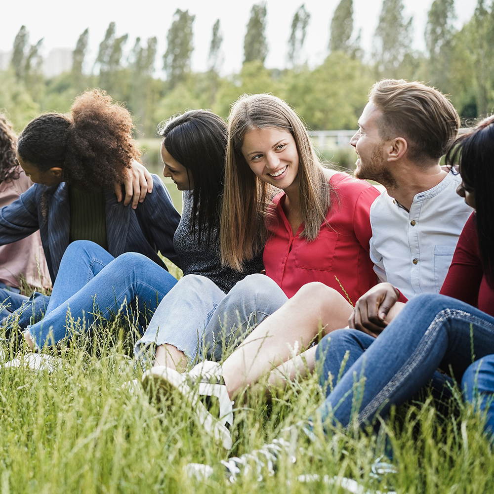 multiethnic friends having fun sitting on grass